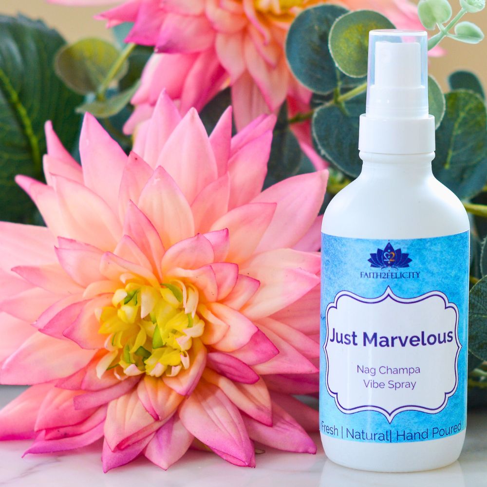 Bottle of 'Just Marvelous' Nag Champa Vibe Spray next to a pink flower with green leaves.